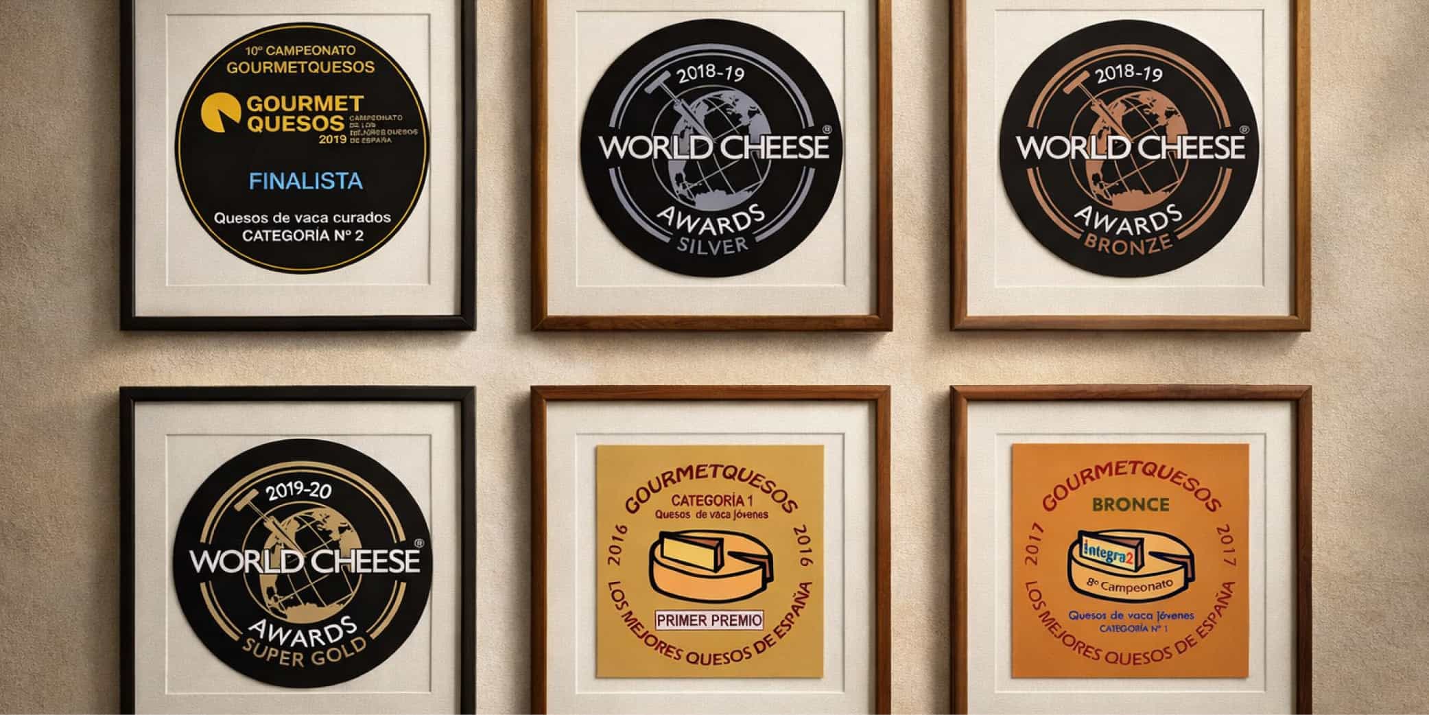 Seis premios de concursos de queso enmarcados y colgados en una pared beige, organizados en una cuadr&iacute;cula 2x3